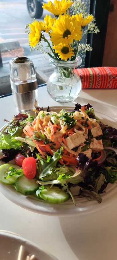 Garden salad by the window with sunflowers on the table