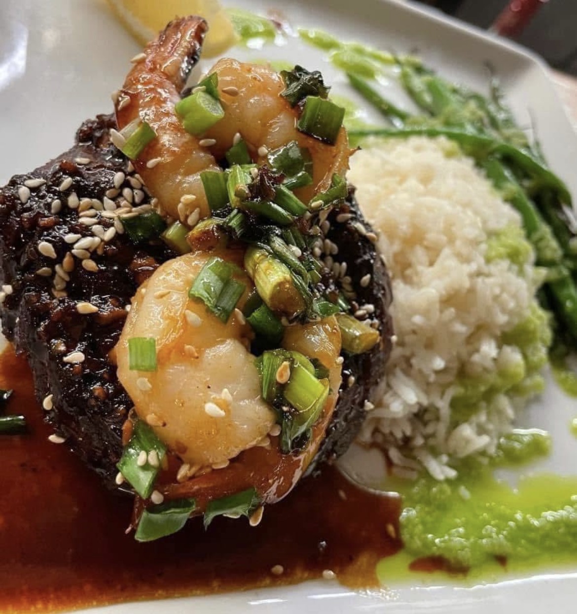 Beef tenderloin topped with sesame glazed shrimp and scallions, with rice and green beans